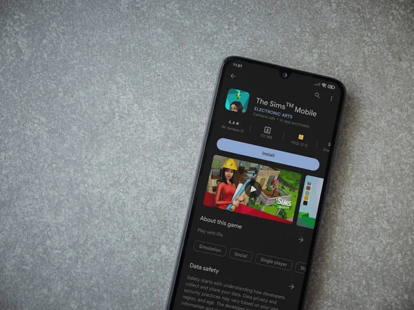 Lod, Israel - July 16,2023: The Sims Mobile app play store page on smartphone on ceramic stone background. Top view flat lay with copy space.