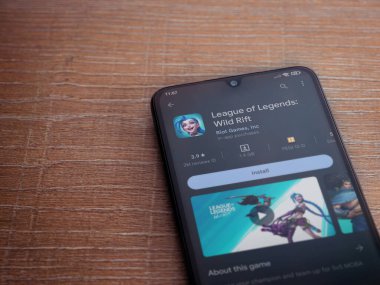 Lod, Israel - July 16,2023: League of Legends - Wild Rift app play store page on smartphone on wooden background. Top view flat lay with copy space.