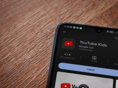 Lod, Israel - July 16,2023: YouTube Kids app play store page on smartphone on wooden background. Top view flat lay with copy space.