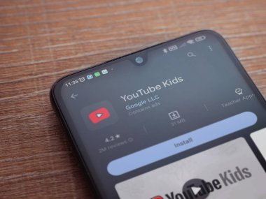 Lod, Israel - July 16,2023: YouTube Kids app play store page on smartphone on wooden background. Top view flat lay with copy space.