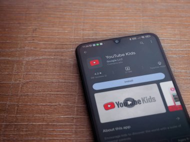 Lod, Israel - July 16,2023: YouTube Kids app play store page on smartphone on wooden background. Top view flat lay with copy space.