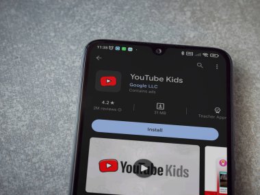 Lod, Israel - July 16,2023: YouTube Kids app play store page on smartphone on ceramic stone background. Top view flat lay with copy space.