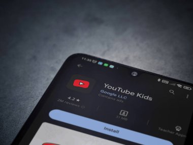 Lod, Israel - July 16,2023: YouTube Kids app play store page on smartphone on a dark marble stone background. Top view flat lay with copy space.