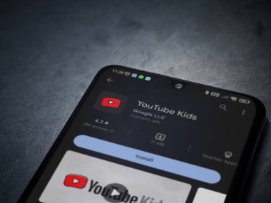 Lod, Israel - July 16,2023: YouTube Kids app play store page on smartphone on a dark marble stone background. Top view flat lay with copy space.