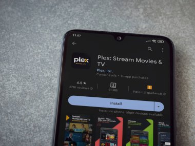 Lod, Israel - July 16,2023: Plex app play store page on smartphone on ceramic stone background. Top view flat lay with copy space.