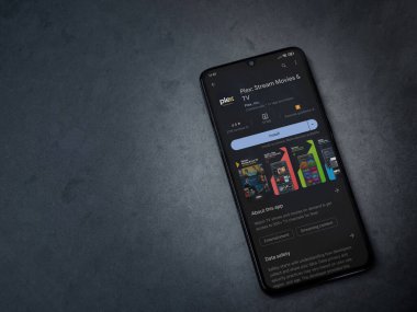 Lod, Israel - July 16,2023: Plex app play store page on smartphone on a dark marble stone background. Top view flat lay with copy space.