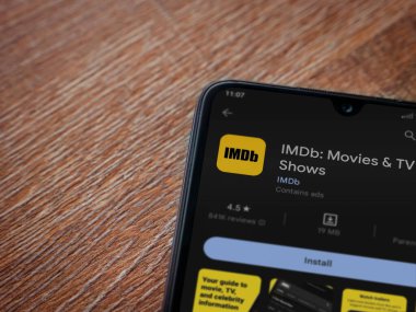 Lod, Israel - July 16,2023: IDMb app play store page on smartphone on wooden background. Top view flat lay with copy space.