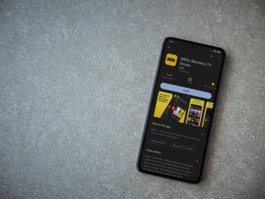 Lod, Israel - July 16,2023: IDMb app play store page on smartphone on ceramic stone background. Top view flat lay with copy space.