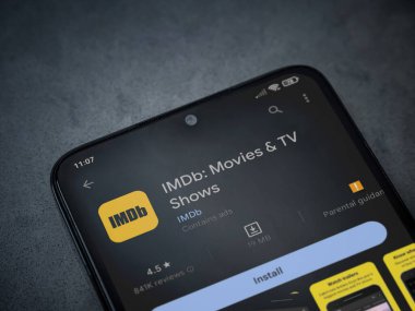 Lod, Israel - July 16,2023: IDMb app play store page on smartphone on a dark marble stone background. Top view flat lay with copy space.