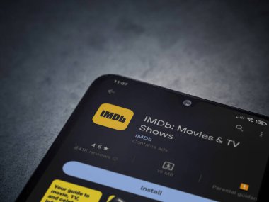 Lod, Israel - July 16,2023: IDMb app play store page on smartphone on a dark marble stone background. Top view flat lay with copy space.