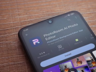 Lod, Israel - July 16,2023: PhotoRoom Studio Photo Editor app play store page on smartphone on wooden background.. Top view flat lay with copy space.