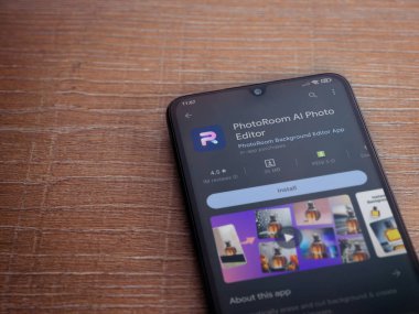 Lod, Israel - July 16,2023: PhotoRoom Studio Photo Editor app play store page on smartphone on wooden background.. Top view flat lay with copy space.