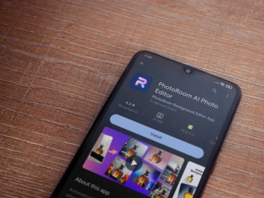 Lod, Israel - July 16,2023: PhotoRoom Studio Photo Editor app play store page on smartphone on wooden background.. Top view flat lay with copy space.