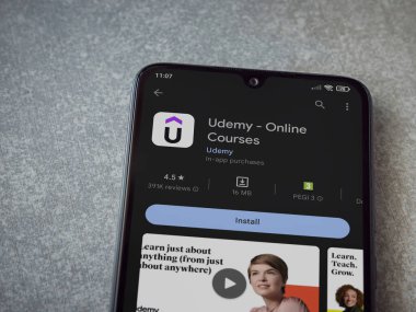 Lod, Israel - July 16,2023: Udemy app play store page on smartphone on ceramic stone background. Top view flat lay with copy space.