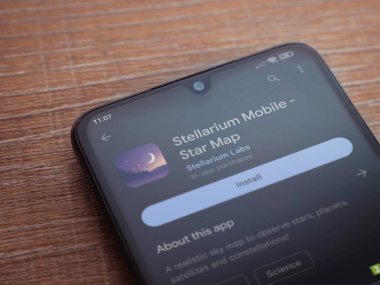 Lod, Israel - July 16,2023: Stellarium - Star Map app play store page on smartphone on wooden background. Top view flat lay with copy space.