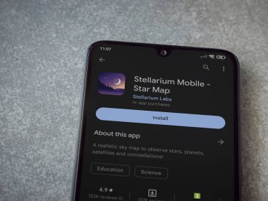 Lod, Israel - July 16,2023: Stellarium - Star Map app play store page on smartphone on ceramic stone background. Top view flat lay with copy space.