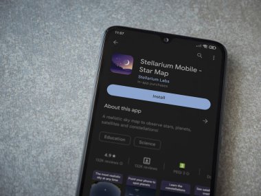 Lod, Israel - July 16,2023: Stellarium - Star Map app play store page on smartphone on ceramic stone background. Top view flat lay with copy space.