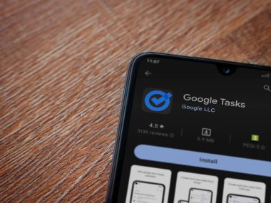 Lod, Israel - July 16,2023: Google Task app play store page on smartphone on wooden background. Top view flat lay with copy space.