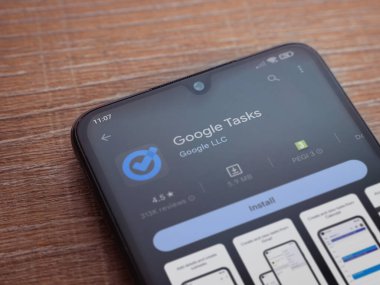 Lod, Israel - July 16,2023: Google Task app play store page on smartphone on wooden background. Top view flat lay with copy space.