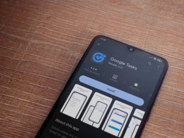Lod, Israel - July 16,2023: Google Task app play store page on smartphone on wooden background. Top view flat lay with copy space.