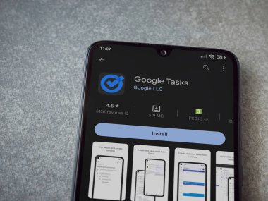 Lod, Israel - July 16,2023: Google Task app play store page on smartphone on ceramic stone background. Top view flat lay with copy space.