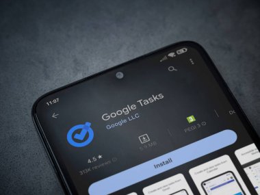 Lod, Israel - July 16,2023: Google Task app play store page on smartphone on a dark marble stone background. Top view flat lay with copy space.