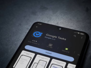 Lod, Israel - July 16,2023: Google Task app play store page on smartphone on a dark marble stone background. Top view flat lay with copy space.