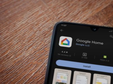 Lod, Israel - July 16,2023: Google Home app play store page on smartphone on wooden background. Top view flat lay with copy space.