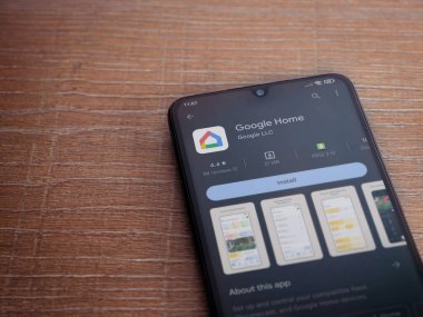Lod, Israel - July 16,2023: Google Home app play store page on smartphone on wooden background. Top view flat lay with copy space.