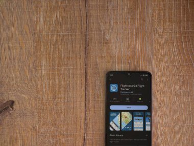 Lod, Israel - July 16,2023: Flightradar24 Flight Tracker app play store page on smartphone on wooden background. Top view flat lay with copy space.