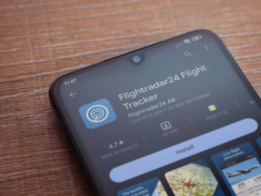 Lod, Israel - July 16,2023: Flightradar24 Flight Tracker app play store page on smartphone on wooden background. Top view flat lay with copy space.