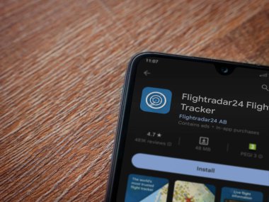 Lod, Israel - July 16,2023: Flightradar24 Flight Tracker app play store page on smartphone on wooden background. Top view flat lay with copy space.
