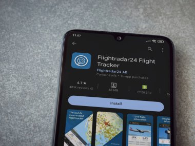 Lod, Israel - July 16,2023: Flightradar24 Flight Tracker app play store page on smartphone on ceramic stone background. Top view flat lay with copy space.