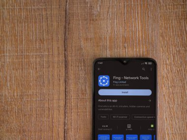Lod, Israel - July 16,2023: Fing app play store page on smartphone on wooden background. Top view flat lay with copy space.