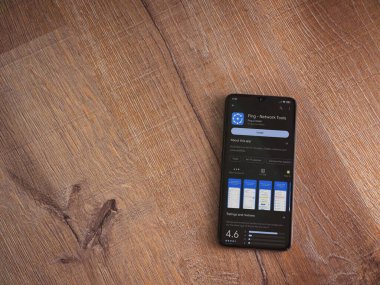 Lod, Israel - July 16,2023: Fing app play store page on smartphone on wooden background. Top view flat lay with copy space.