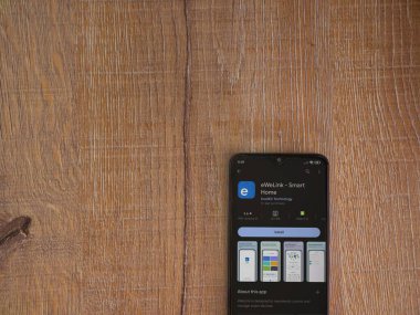 Lod, Israel - July 16,2023: eWeLink app play store page on smartphone on wooden background. Top view flat lay with copy space.