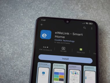 Lod, Israel - July 16,2023: eWeLink app play store page on smartphone on ceramic stone background. Top view flat lay with copy space.