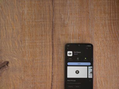 Lod, Israel - July 16,2023: DJI Store app play store page on smartphone on wooden background. Top view flat lay with copy space.