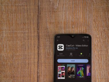 Lod, Israel - July 16,2023: CapCut app play store page on smartphone on wooden background.. Top view flat lay with copy space.