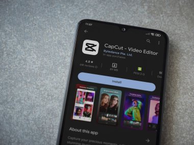 Lod, Israel - July 16,2023: CapCut app play store page on smartphone on ceramic stone background.. Top view flat lay with copy space.