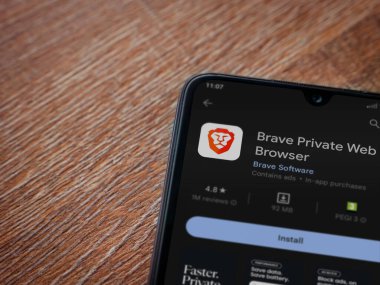 Lod, Israel - July 16,2023: Brave Private Browser app play store page on smartphone on wooden background. Top view flat lay with copy space.