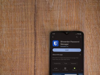 Lod, Israel - July 16,2023: Bitwarden Password Manager app play store page on smartphone on wooden background. Top view flat lay with copy space.