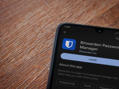 Lod, Israel - July 16,2023: Bitwarden Password Manager app play store page on smartphone on wooden background. Top view flat lay with copy space.