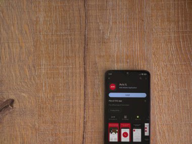 Lod, Israel - July 16,2023: Avis IL app play store page on smartphone on wooden background. Top view flat lay with copy space.