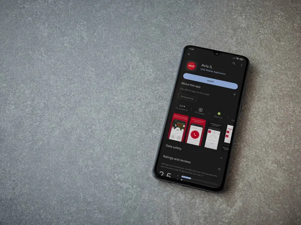Lod, Israel - July 16,2023: Avis IL app play store page on smartphone on ceramic stone background. Top view flat lay with copy space.