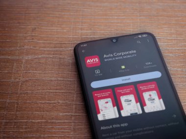 Lod, Israel - July 16,2023: Avis Corporate app play store page on smartphone on wooden background. Top view flat lay with copy space.