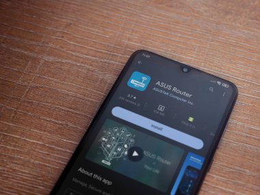 Lod, Israel - July 16,2023: ASUS Router app play store page on smartphone on wooden background. Top view flat lay with copy space.