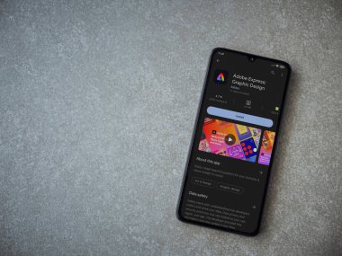 Lod, Israel - July 16,2023: Adobe Express - Graphic Design app play store page on smartphone on ceramic stone background. Top view flat lay with copy space.