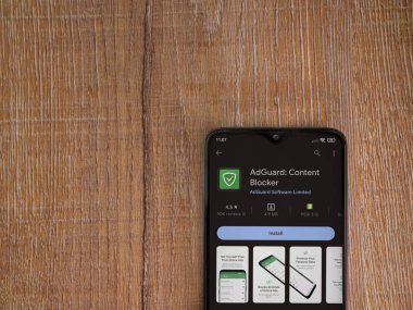 Lod, Israel - July 16,2023: AdGuard app play store page on smartphone on wooden background. Top view flat lay with copy space.