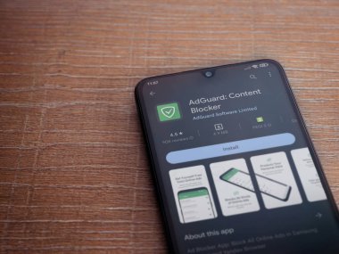 Lod, Israel - July 16,2023: AdGuard app play store page on smartphone on wooden background. Top view flat lay with copy space.